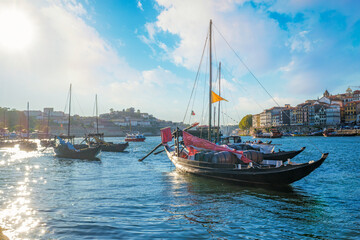 Fototapeta premium Rabelo boats on Douro River by Porto Ribeira with visible wine company names, barrels and waterfront detail near Dom Luis I Bridge