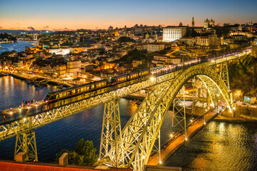 Fototapeta premium Night city view of Porto and Ribeira with a tram on illuminated Dom Luis I Bridge above the Douro River in Portugal