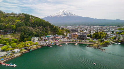 Naklejka premium Scenic drone view of Mount Fuji rising behind the calm waters of Lake Kawaguchiko