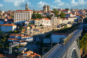 Obraz premium Telephoto city view of Porto and Ribeira with a tram on Dom Luis I Bridge above the Douro River in Portugal from Serra do Pilar