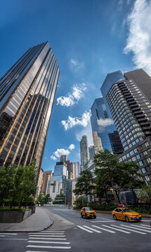 New york, usa august 19,2024. High rise buildings dominating the cityscape under a clear blue sky, showing yellow taxis traveling on a street in manhattan
