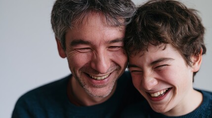 Obraz premium Father and disabled son laughing together at home, authentic joyful family moment