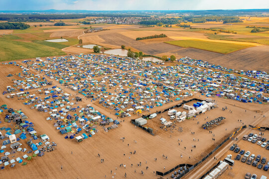 Herzogenaurach, Germany - 22 July 2022: Aerial view of Open Beatz Festival campsite with thousands of tents spread across fields under a warm sunset light.