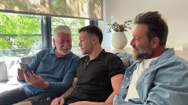 Three Generations Of Men Sharing Happy Moments On A Smartphone At Home