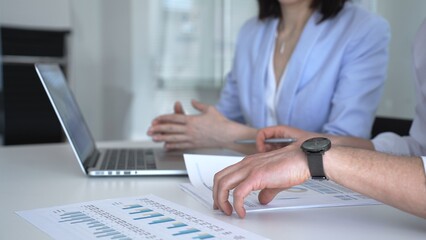 Fototapeta premium Business professionals collaborating and analyzing financial data charts on a laptop during corporate meeting, discussing economic growth strategies and market trends