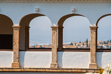 Naklejka premium Alhambra arches creating a historical viewpoint, framing the UNESCO World Heritage city of Granada and the traditional Albaicin neighborhood on a clear day in Spain