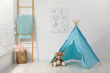Wigwam, toy bear and wooden ladder near white wall in child's room © New Africa