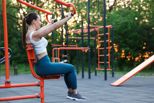 Athletic woman exercising on chest press machine at outdoor gym. Space for text