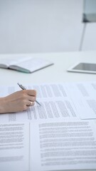 Fototapeta premium Businesswoman signing legal document on an office desk, reviewing terms of a contract or agreement before endorsing it, completing an important corporate transaction
