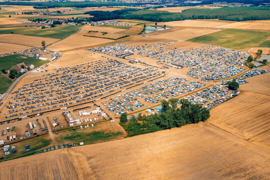 Herzogenaurach, Germany - 22 July 2022: Aerial view of the Open Beatz Festival campsite with rows of tents and parked cars surrounded by agricultural fields.