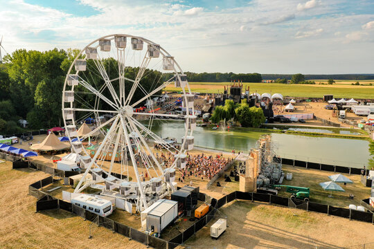 Herzogenaurach, Germany - 22 July 2022: Aerial view of Open Beatz Festival featuring a large white Ferris wheel, festival stages, and crowds of people in the green fields of Bayern.