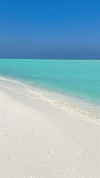 Clear turquoise ocean water and white sand on a peaceful tropical beach. Relaxing summer vacation scene with blue sky and paradise island atmosphere.
