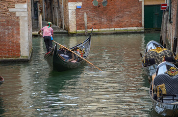 Italy, Venice, September 30, 2025, A gondolier in a red and white striped shirt is transporting tourists in Venice © Pawel Filusz
