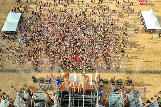 Herzogenaurach, Germany - 22 July 2022: Aerial view of Open Beatz Festival with a massive crowd gathered in front of the main stage, white tents and golden sunlight.