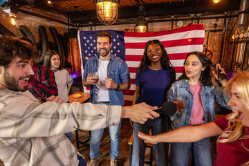 Obraz premium Group of friends fully immersed in karaoke singing in pub