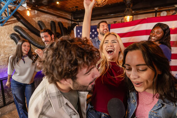 Fototapeta premium Energetic karaoke party with friends and American flag in pub