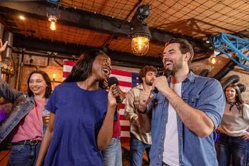 Fototapeta premium Friends singing and celebrating karaoke night in pub with USA flag