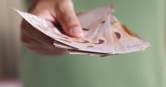 Male hand giving Thai banknotes representing payment, spending, money, finance, cash, business transactions, cash exchange, income, and financial concepts, close-up