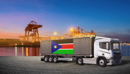 South Sudan Logistics: A cargo truck carrying a shipping container adorned with the South Sudan flag stands ready at a bustling port, symbolizing international trade and transport at dawn. © bao