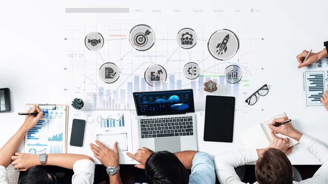 A diverse group of professionals collaborates on business strategy using a laptop and charts, focusing on data visualization to enhance performance and drive growth. Raster