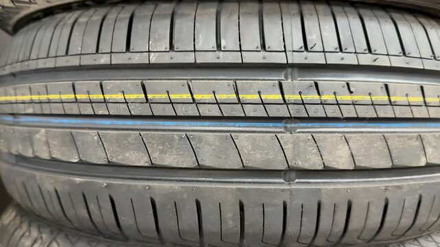 Closeup summer car tire tread detail showing new showroom display with colored stripes, grooves and textured rubber, highlighting
