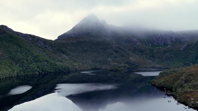 Zoom in to the peak of Cradle mountain over Lake Dove in Tasmanian national park aerial view.