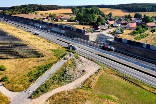 Nurnberg, Germany - 18 May 2024: Aerial view of the A73 highway with traffic, noise protection walls, and adjacent residential houses.