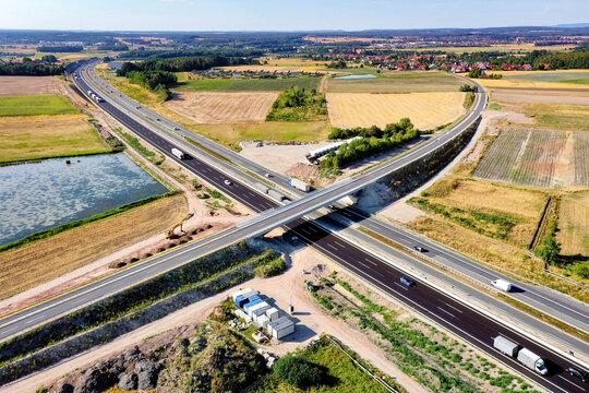Nurnberg, Germany - 18 May 2024: Aerial view of the A73 motorway junction with traffic flowing past agricultural fields and rural landscapes under a clear sky.