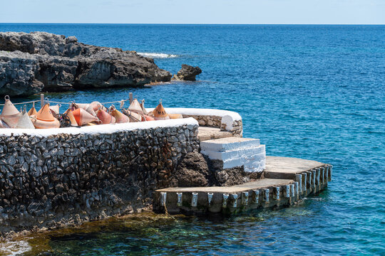 Traditional stone pier with mooring buoys on the rocky coast of Binibeca, Menorca. Maritime dock infrastructure, nautical sailing lifestyle, and summer vacation concept.