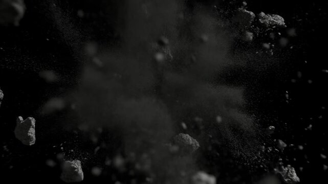 Static shot of dark asteroid exploding and fragmenting into rocks and dust on black space background