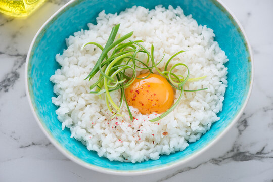 Turquoise bowl with tamago kake gohan or white rice mixed with a raw chicken egg, horizontal shot, middle close-up