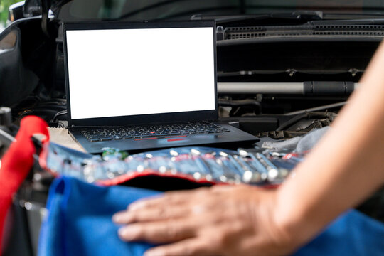 A laptop computer sits on a vehicle's engine block during a computer-aided diagnostic check.