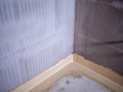 Bathroom waterproofing and hydro insulation applied on walls and floor corner during renovation before tiling installation.