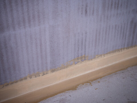 Bathroom waterproofing and hydro insulation applied on walls and floor corner during renovation before tiling installation.
