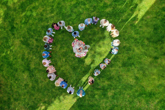 Wiesenthau, Germany - 02 May 2026: Aerial view of a wedding party forming a heart shape on the green lawn of Schloss Wiesenthau with the bride and groom in the center.