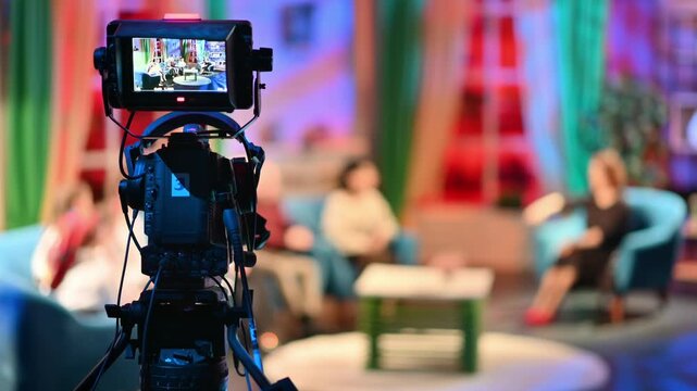 Professional television camera filming talk show guests in studio broadcast setting.