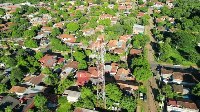 A residential area with a tall tower in the middle. The houses are small and close together. There are trees and a street in the background