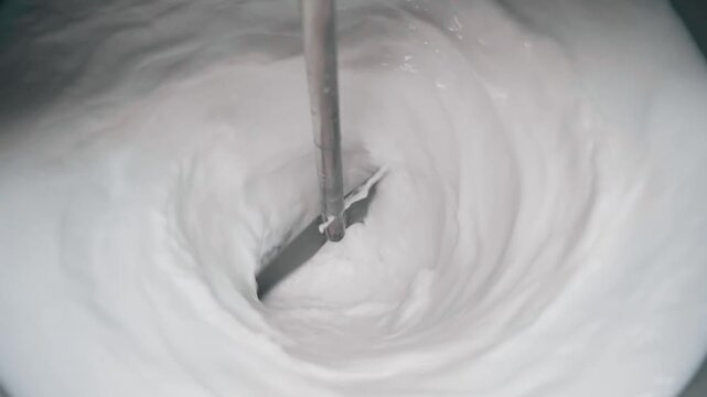 close up shot of a huge blinder with milk inside a container in cheese factory
