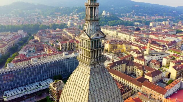 Turin, Italy. Mole Antonelliana, soaring brick spire and ribbed dome with layered colonnade, aerial drone orbit over the historic cityscape under clear daylight. Drone footage, Point of interest