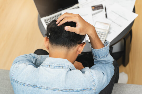 Household financial economic concept, Stressed Young Asian adults are looking at credit card bills issued documents, and apartment loan mortgages and worrying about having no money to pay.