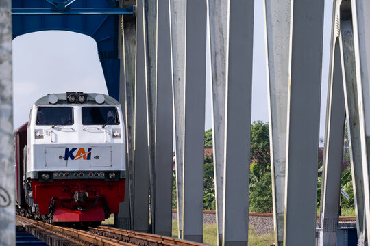 Kebumen, Indonesia - May 14, 2026: KAI passenger train led by a CC206 locomotive crossing the historic Renville truss bridge in Central Java.