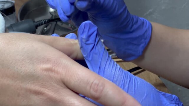Video of a nail technician filing nails. Manicurist shapes nail using salon nail file during cosmetic procedure in beauty salon. Woman gets a french manicure at a beauty salon, manicurist files her cu