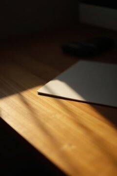 L&iacute;nea de luz solar sobre el escritorio, contraste sutil sobre la hoja de papel