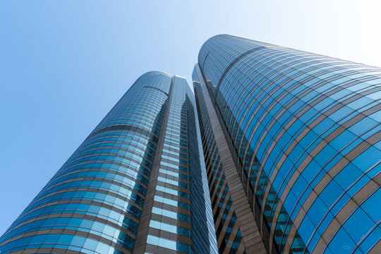 Low angle view of modern skyscrapers against clear blue sky in financial district, showcasing urban architecture, business growth, corporate environment and future city development concept