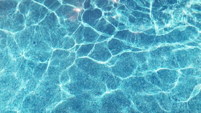 The clear water in the pool gleams and reflects the rays of the sun on a summer day