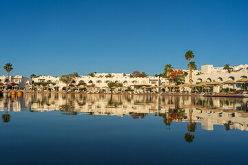 Obraz premium Beautiful panoramic view of a tropical hotel resort on the coast with traditional Arabic architecture perfectly reflecting in mirror-like water, Sharm El Sheikh , Egypt