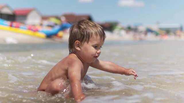 Kid collects shells and pebbles in the sea on a sandy bottom under the summer sun on a vacation
