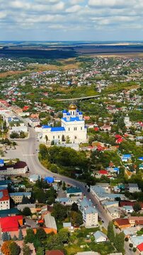 Vertical video. Yelets, Lipetsk region, Russia. Cathedral of the Ascension, white walls and gilded domes rising above the historic city center, Drone footage over the Sosna River under bright summer 