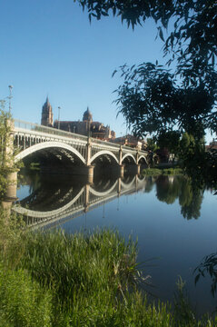 Old iron bridge crossing the river Tormes in Salamanca with the cathedral in the backgrouns. Spain.