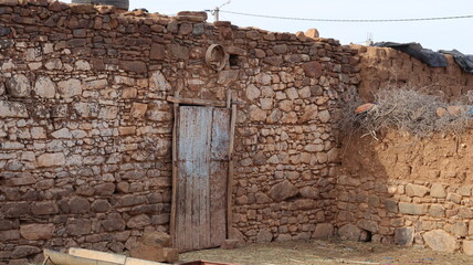 Naklejka premium Weathered blue wooden door in traditional Moroccan stone wall